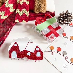 Close-up of sparkling Christmas gift box and snow cabin hair claws with festive decor