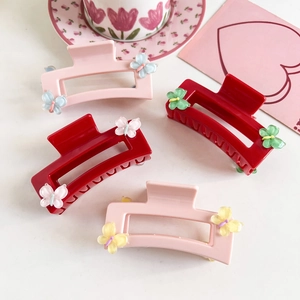 Detail of four square hair claws in pink and red with colorful 3D resin butterflies