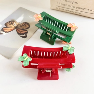 Detail of red and green rectangular hair claws with resin flowers in a two-piece set