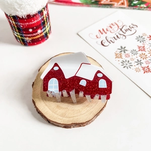 Detailed view of a red glitter house-shaped Christmas hair claw clip on a wooden base