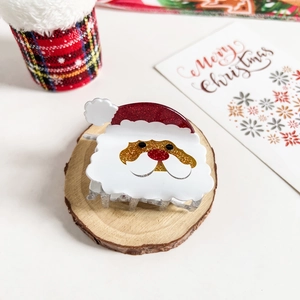 Detailed view of Santa Claus hair claw clip with red and gold glitter accents on wood
