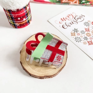 Detail of Christmas gift box hair claw with silver glitter and red ribbon design
