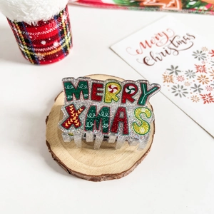 Detail of glittery Merry Xmas hair claw clip on rustic wood with holiday decorations