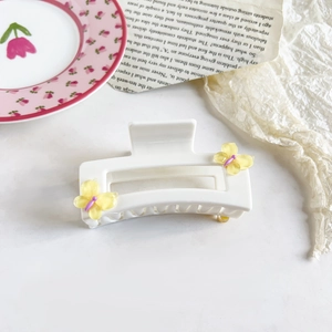Detailed view of cream resin square hair claw clip with yellow butterfly accents and purple dots