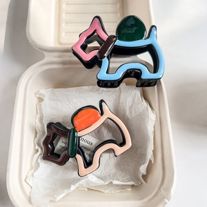 Detailed top view of dog-shaped hair claws in blue and pink inside a minimalist gift box