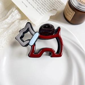 Detail of a red and black dog-shaped hair claw clip made of acetic acid on a white tray
