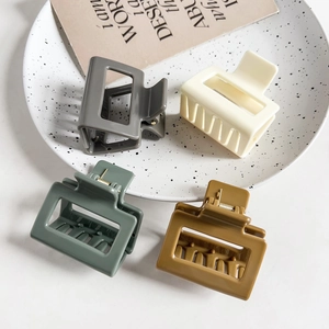 Detail of matte rectangular hair claws in Morandi colors displayed on a ceramic plate
