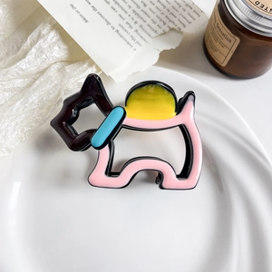 Detail of colorful dog-shaped hair claw clip in acetate finish on decorative tray