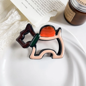 Detail of dog-shaped claw clip in contrasting colors on a white ceramic plate setting