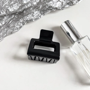 Macro shot of a glossy black rectangular hair claw clip with silver textured decor