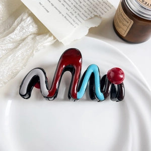 Close-up of wavy color-block hair claw clip with colorful resin design on white plate