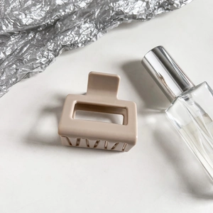Close-up of matte beige square claw clip with frosted texture and hollowed-out design
