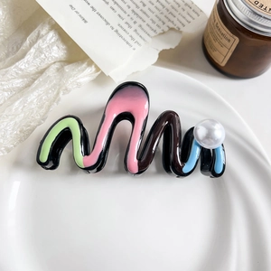 Detailed view of wave-shaped hair claw clip with colorful resin inserts and large faux pearl
