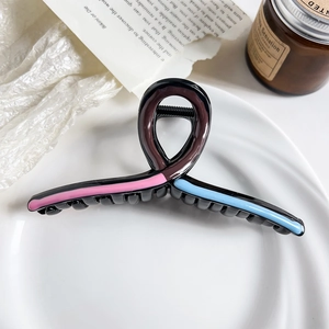 Detail of coffee resin hair claw clip with pink and blue stripes on ceramic plate