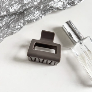 Detail of a matte dark coffee rectangular hair claw clip on a minimalist gray background