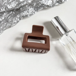 Detail of a brown square hollow hair claw clip with a glossy finish on a white background