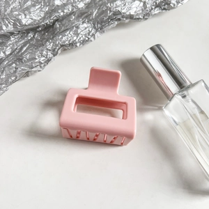 Detail of matte macaron pink square hair claw clip with cross-teeth design on white surface