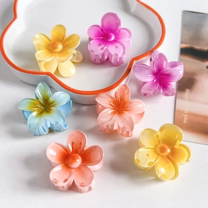 Detailed view of seven colorful resin plumeria flower hair clips on a white ceramic plate