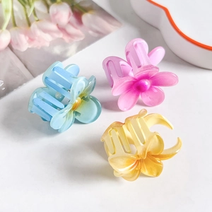 Three small matte plumeria hair claws in pastel blue, pink, and yellow for summer styles