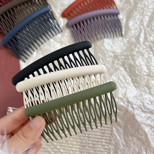 Close-up of 15-tooth matte hair combs in various Morandi colors being held by hand