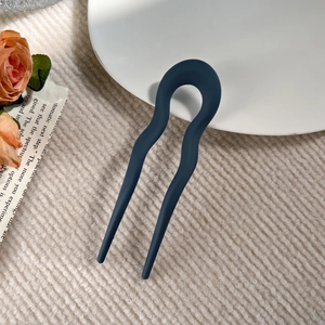 Detail of matte dark blue U-shaped wavy hair pin on a stylish minimalist background