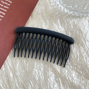 Detail of matte black 14-tooth hair comb on aesthetic minimalist textured background