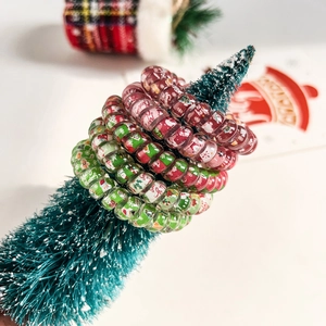 Close-up of spiral Christmas hair ties with Santa and tree prints on a mini tree