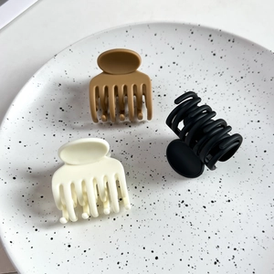 Lot de trois pinces à cheveux mates en marron, noir et beige sur un plateau en céramique