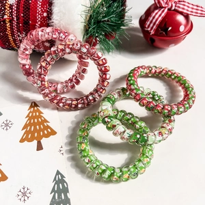 Close-up of five spiral hair ties with Christmas patterns like Santa and snowflakes