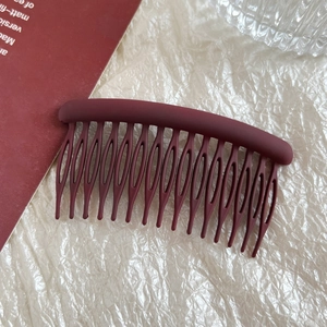 Close-up of matte dark red 15-tooth round hair comb for fixing bangs and hair styling