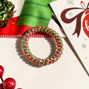 Macro shot of spiral hair tie with festive red green Christmas patterns and Merry text