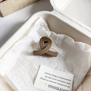 Detalle de una pinza para el pelo marrón mate en una caja de regalo beige con luz suave
