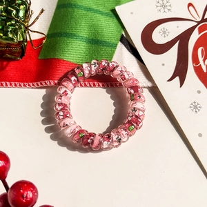 Detail of Christmas spiral hair tie featuring Santa and Merry Christmas motifs