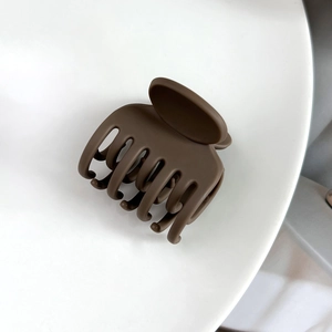 Détail d'une pince à cheveux mate marron foncé à sept dents avec un design en arc lisse
