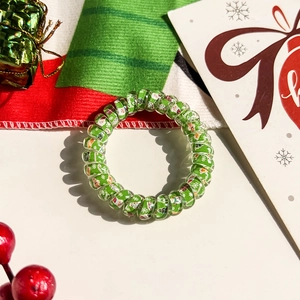 Macro view of green spiral hair tie with Christmas motifs and festive decorations