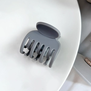 Détail d'une pince à cheveux mate gris foncé avec un design antidérapant à 7 dents