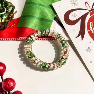 Detail of a spiral Christmas hair tie with Merry Christmas prints on a festive background