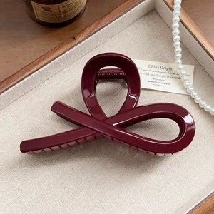 Close-up of a glossy deep wine red shark hair claw clip with elegant twisted design
