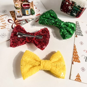 Gros plan de nœuds de Noël à paillettes rouges, verts et jaunes avec pinces en métal