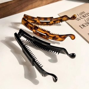 Close-up of tortoise shell and black banana clips with anti-slip teeth on a desk