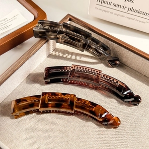 Detail of matte banana hair clips in amber and tortoiseshell on an elegant tray
