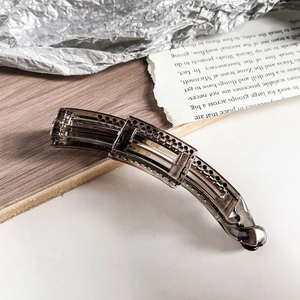 Detail of a dark brown translucent resin banana clip with elegant cutout rectangular frames