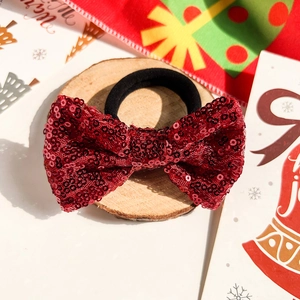 Détail d'un chouchou nœud de Noël à paillettes rouges avec élastique noir solide
