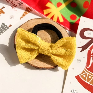 Détail d'un chouchou à nœud en paillettes jaunes avec maille brillante sur socle boisé