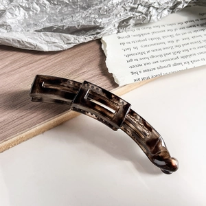 Detailed view of a brown tortoiseshell banana hair clip on a stylish decorative background