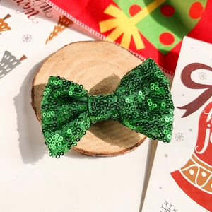 Détail d'un chouchou à nœud pailleté vert sur une tranche de bois au décor festif
