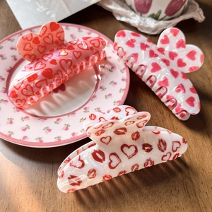 Detailed view of heart-shaped hair claw clips with rose and lip prints on a ceramic plate