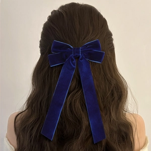 Elegant navy blue velvet bow hair clip with long ribbons worn on wavy brown hair