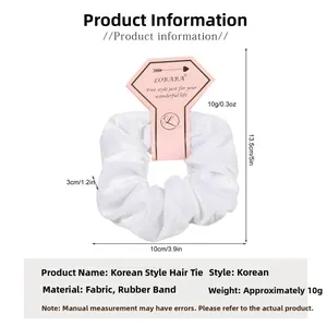 Macro shot of 10cm white velvet scrunchie with dimensions and brand card packaging