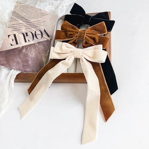 Close-up of velvet ribbon bow hair clips in black, brown, and cream with long streamers